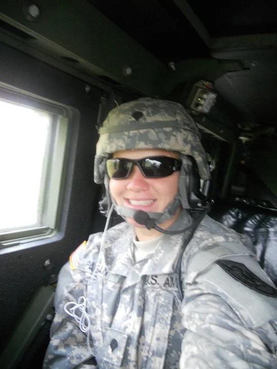 Tania smiling in helmet and sunglasses inside a military vehicle